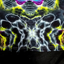Close-up of a black fabric with a highly reflective, symmetrical chrome or metallic foil pattern in white, bright yellow, and purple.