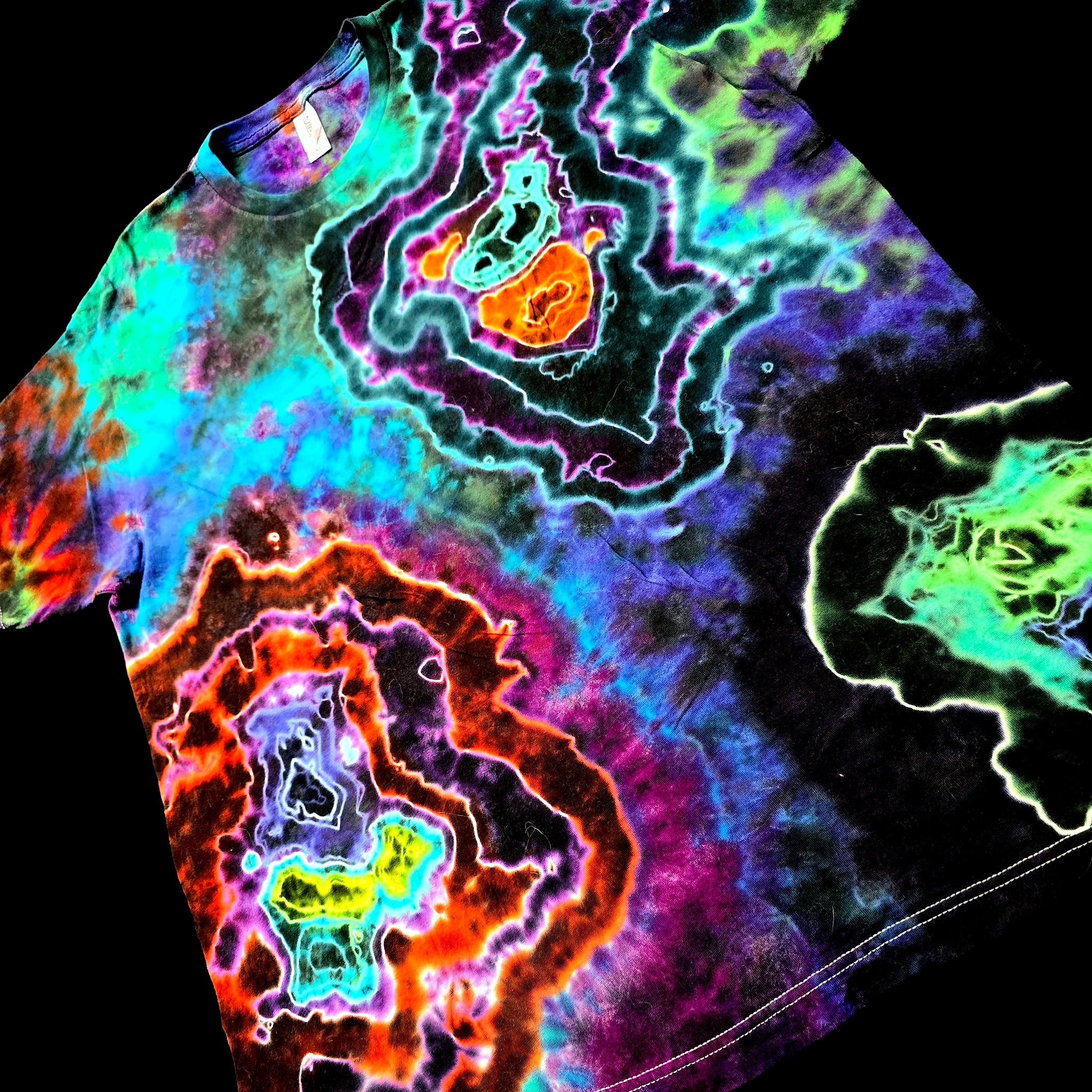 A short-sleeve crewneck t-shirt featuring a vibrant, multicolor psychedelic tie-dye pattern with glowing neon-like concentric shapes in purple, blue, green, orange, and red against a black background.