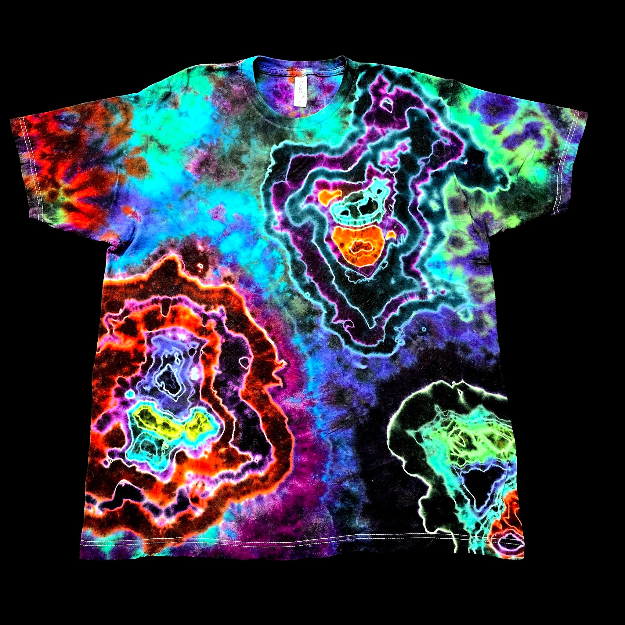 A short-sleeve crewneck t-shirt featuring a vibrant, multicolor neon tie-dye pattern with concentric geode-like shapes in purple, green, blue, orange, and red on a black background.
