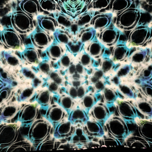 A close-up of a tie-dye fabric with a symmetrical, kaleidoscopic pattern featuring black, white, bright cyan blue, and subtle purple accents.