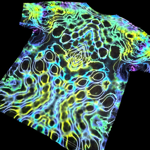 A short-sleeve crewneck t-shirt featuring a vibrant, multicolor neon pattern of wavy lines and circular shapes in yellow, green, blue, and purple over a black base, shown against a solid black background.