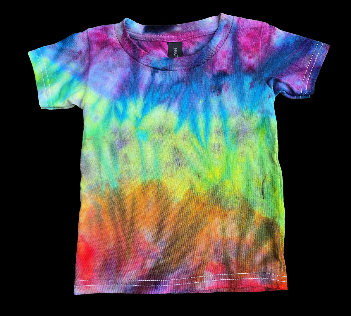 A short-sleeve kids' tie-dye t-shirt with a vibrant rainbow gradient pattern, laid flat against a solid black background.
