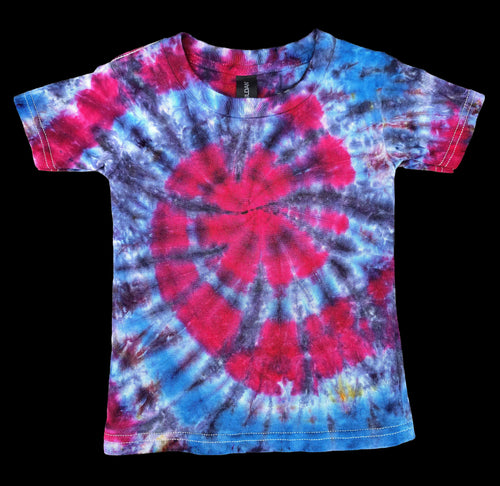 A short-sleeve tie-dye t-shirt with a spiral pattern in vibrant pink, blue, and purple, displayed flat against a solid black background.