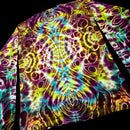 A close-up of a tie-dye patterned fabric, likely a shirt or towel, featuring a vibrant psychedelic design with concentric circles and wavy lines in purple, yellow, green, blue, and orange on a black background.