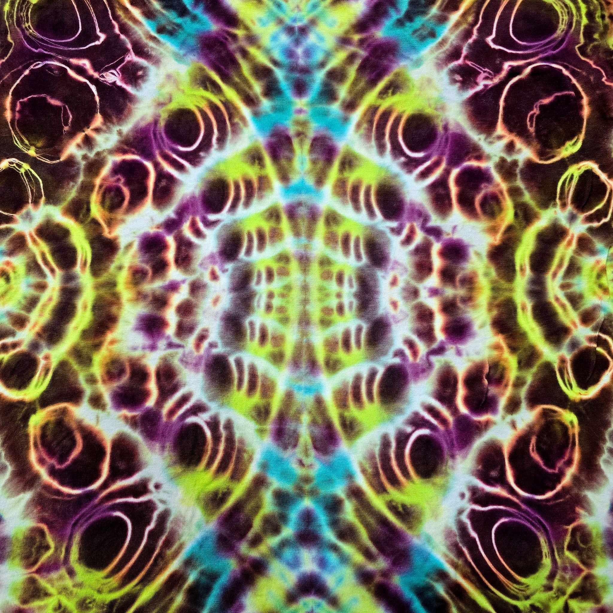 A symmetrical psychedelic tie-dye pattern with neon green, purple, blue, and orange concentric oval motifs filling the frame.