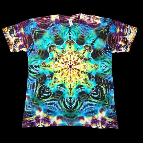 A short-sleeve crewneck t-shirt featuring a vibrant, symmetrical psychedelic mandala tie-dye pattern in shades of blue, yellow, purple, and green, displayed flat against a solid black background.