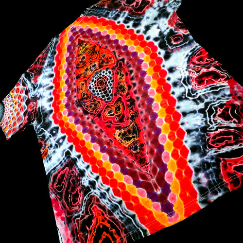 A close-up of a tie-dye t-shirt featuring a prominent central paisley-like motif with concentric hexagonal dots in red, orange, yellow, and purple, surrounded by black, white, and red marbled patterns.