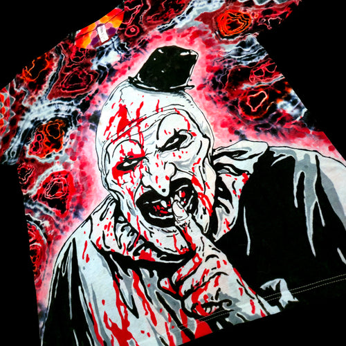 A close-up of a graphic print featuring a horror clown character with blood splatters, set against a swirling red, black, and white background.