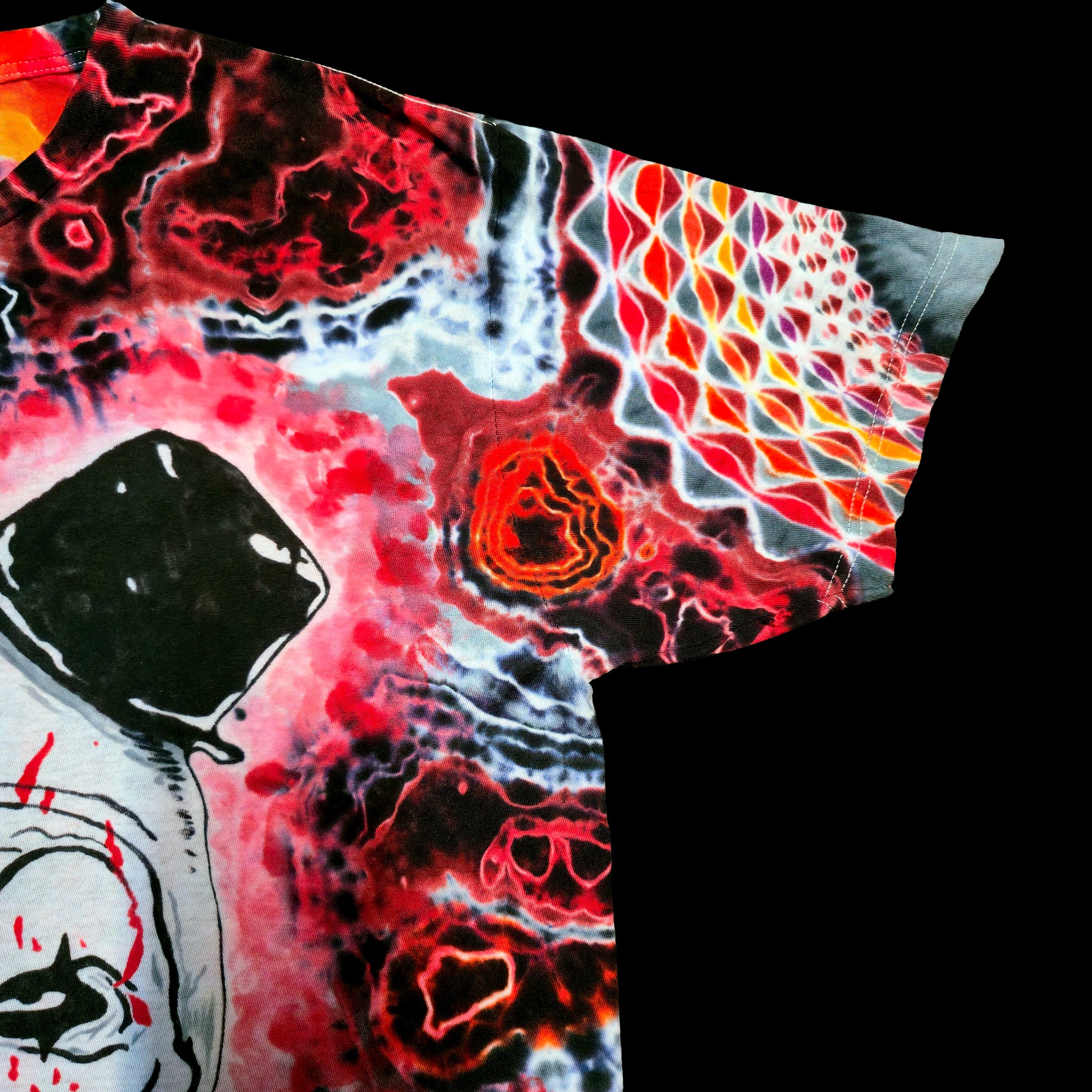 A close-up of a short-sleeve t-shirt featuring a highly vibrant, psychedelic abstract print with red, black, white, and orange patterns, set against a solid black background.