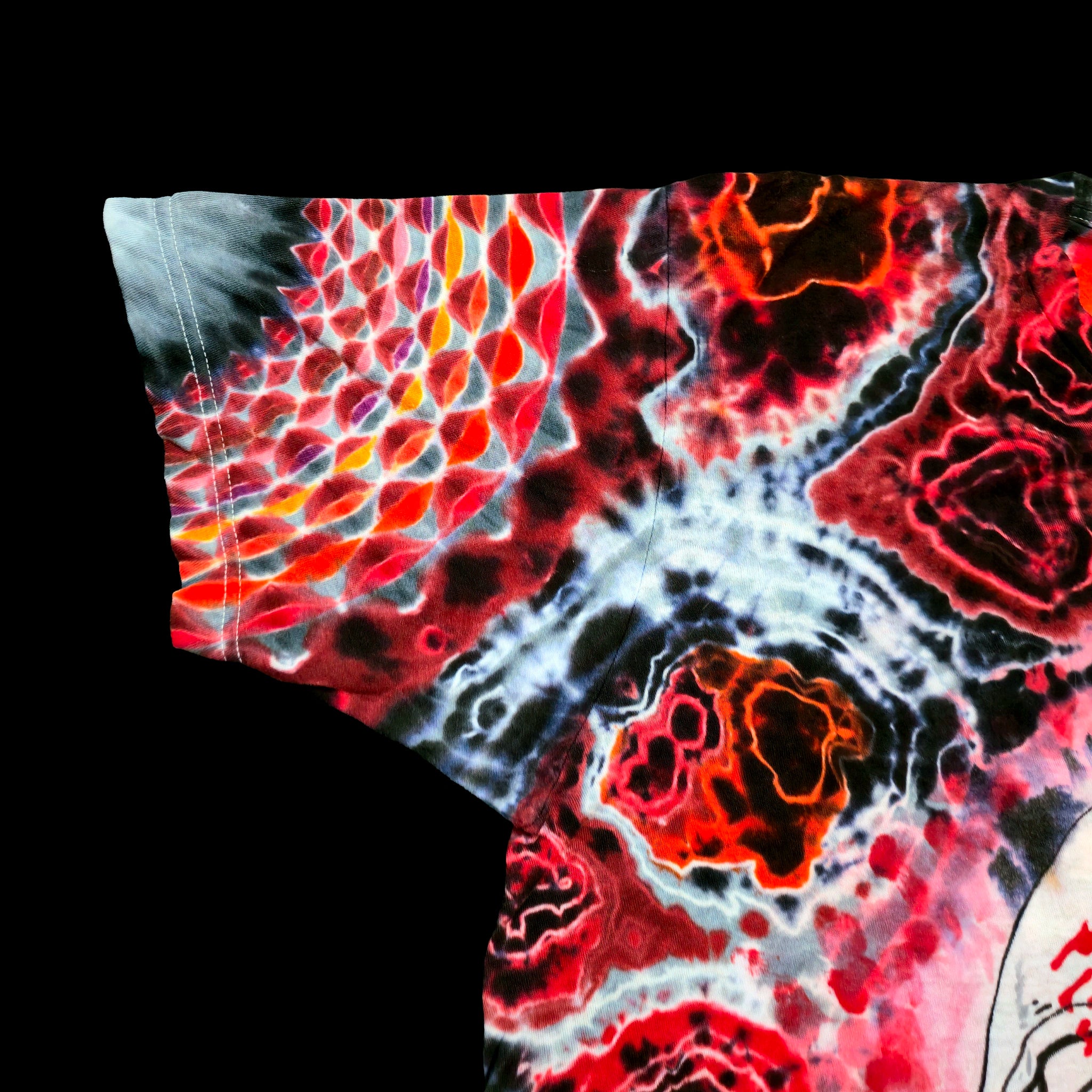 A close-up of a short-sleeve t-shirt featuring a vibrant, multicolor abstract print with red, orange, black, and white organic patterns, set against a solid black background.