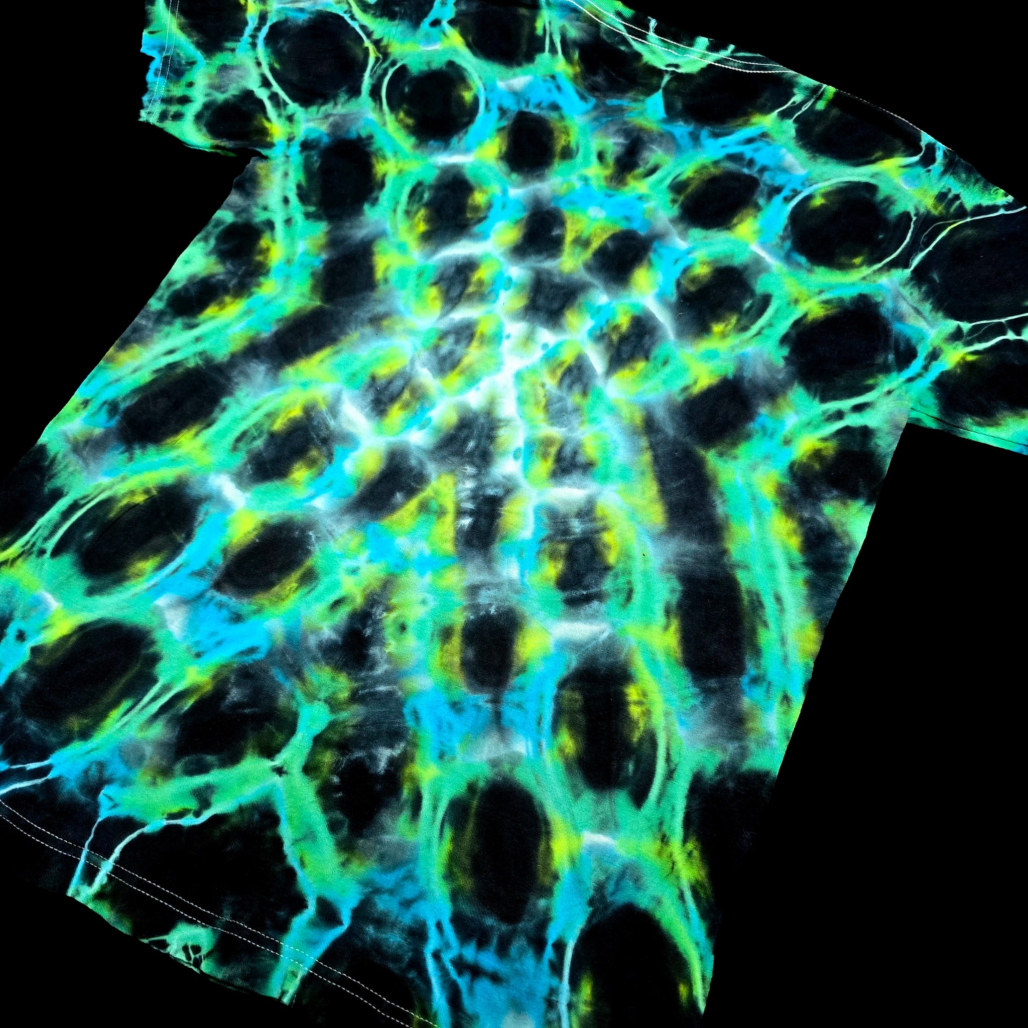 A close-up of a tie-dye fabric pattern featuring a bright neon green and cyan mesh structure over a black background.