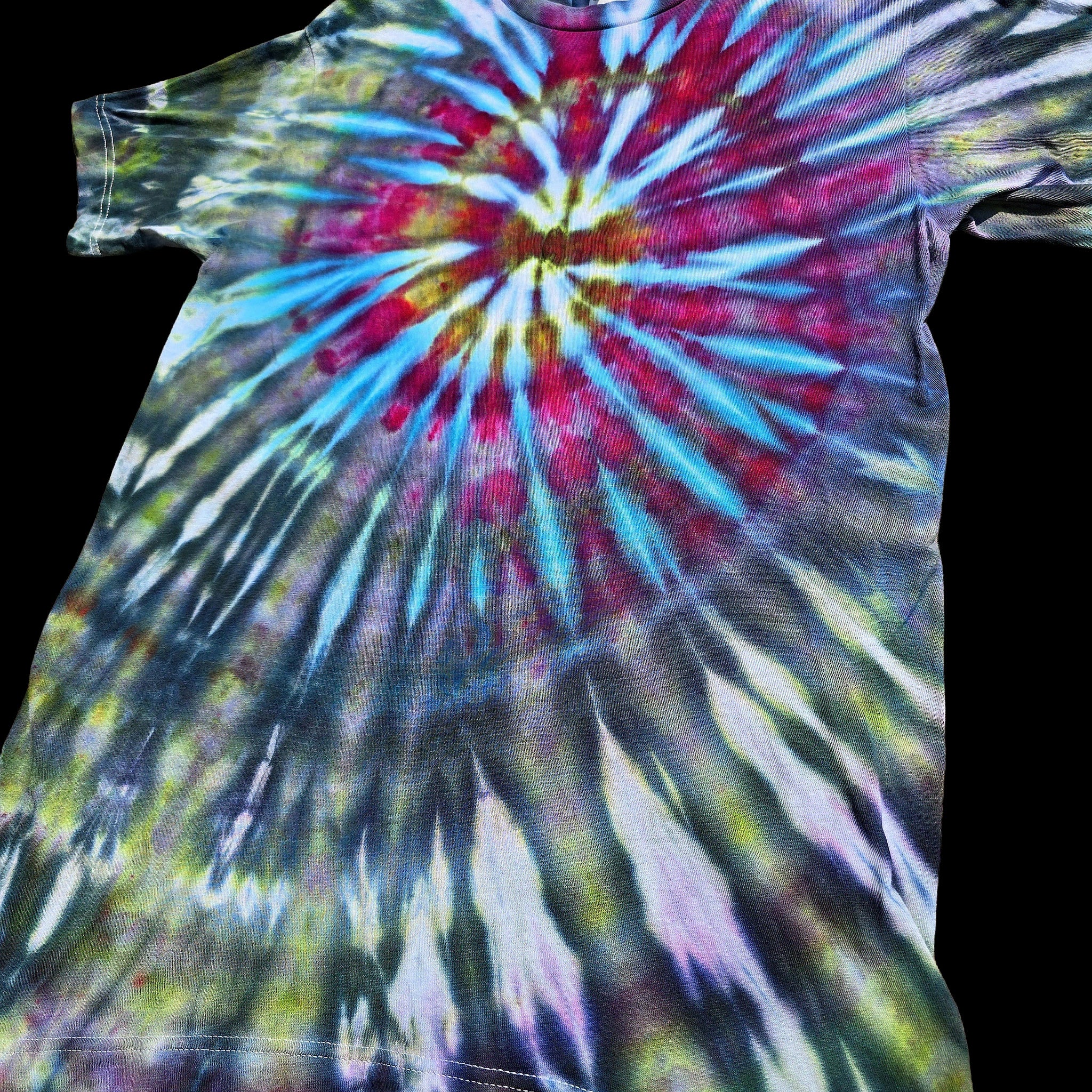 A short-sleeve crewneck tie-dye t-shirt featuring a vibrant spiral burst pattern in blue, magenta, yellow and pink against muted green and purple.  