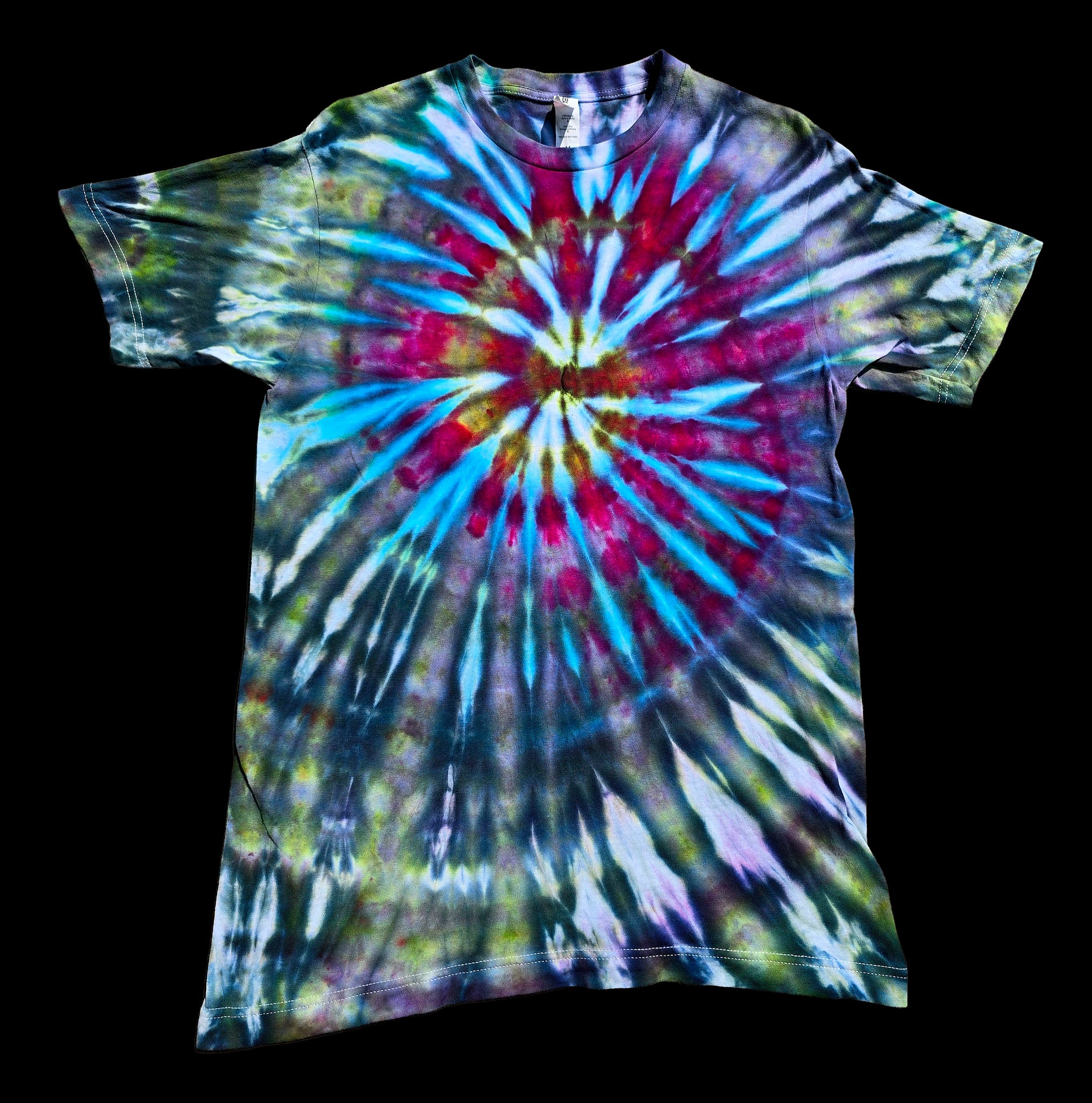 A short-sleeve crewneck tie-dye t-shirt featuring a vibrant spiral burst pattern in blue, magenta, yellow and pink against muted green and purple.  
