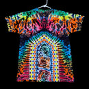 A short-sleeve tie-dye T-shirt hanging on a white hanger against a solid black background. The shirt features a highly vibrant, symmetrical psychedelic pattern with a rainbow of neon colors including blue, green, yellow, orange, pink, and purple.