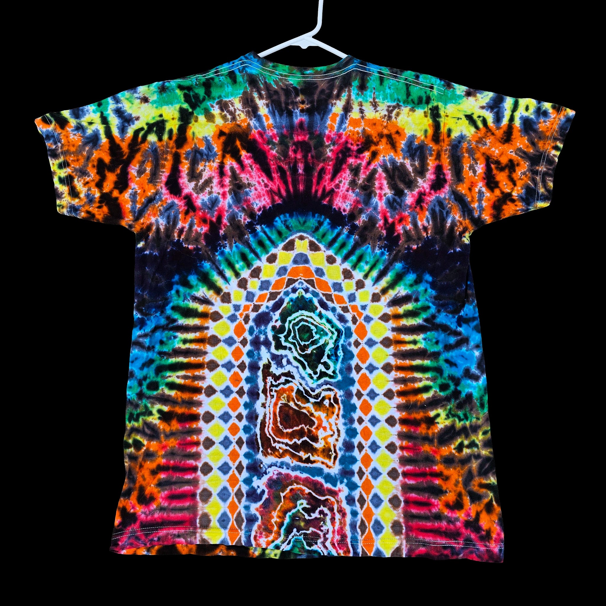 A short-sleeve tie-dye T-shirt hanging on a white hanger against a solid black background. The shirt features a highly vibrant, symmetrical psychedelic pattern with a rainbow of neon colors including blue, green, yellow, orange, pink, and purple.