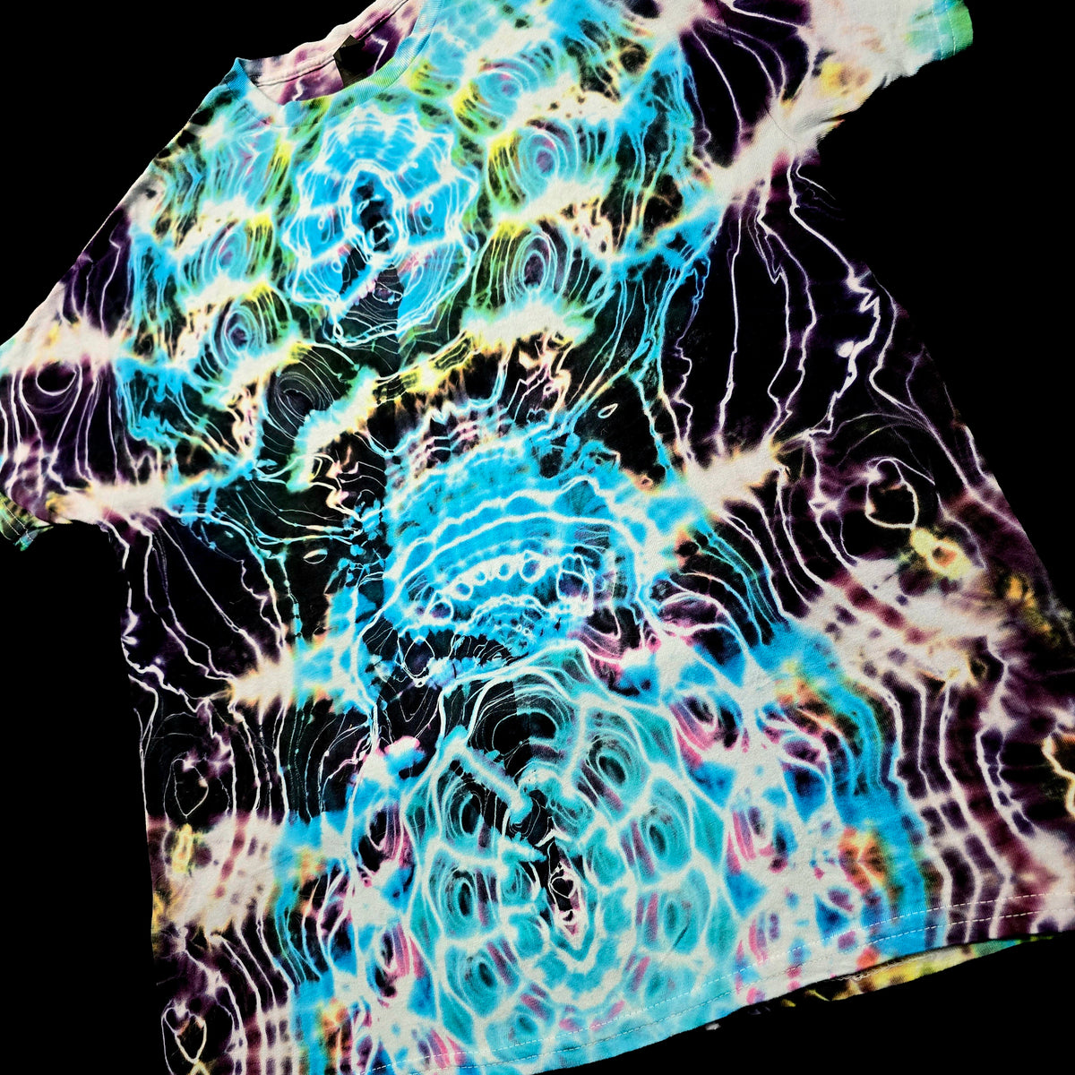 A short-sleeve t-shirt with a vibrant, psychedelic tie-dye pattern featuring swirling waves of turquoise, purple, yellow, and white on a black base, shown against a solid black background.
