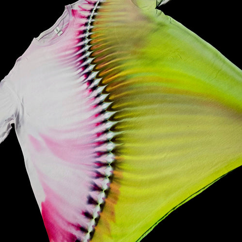 A tie-dye t-shirt laid flat against a solid black background, showcasing a vibrant color-shifting pattern that transitions from white and magenta on the left to a bright neon yellow-green on the right.