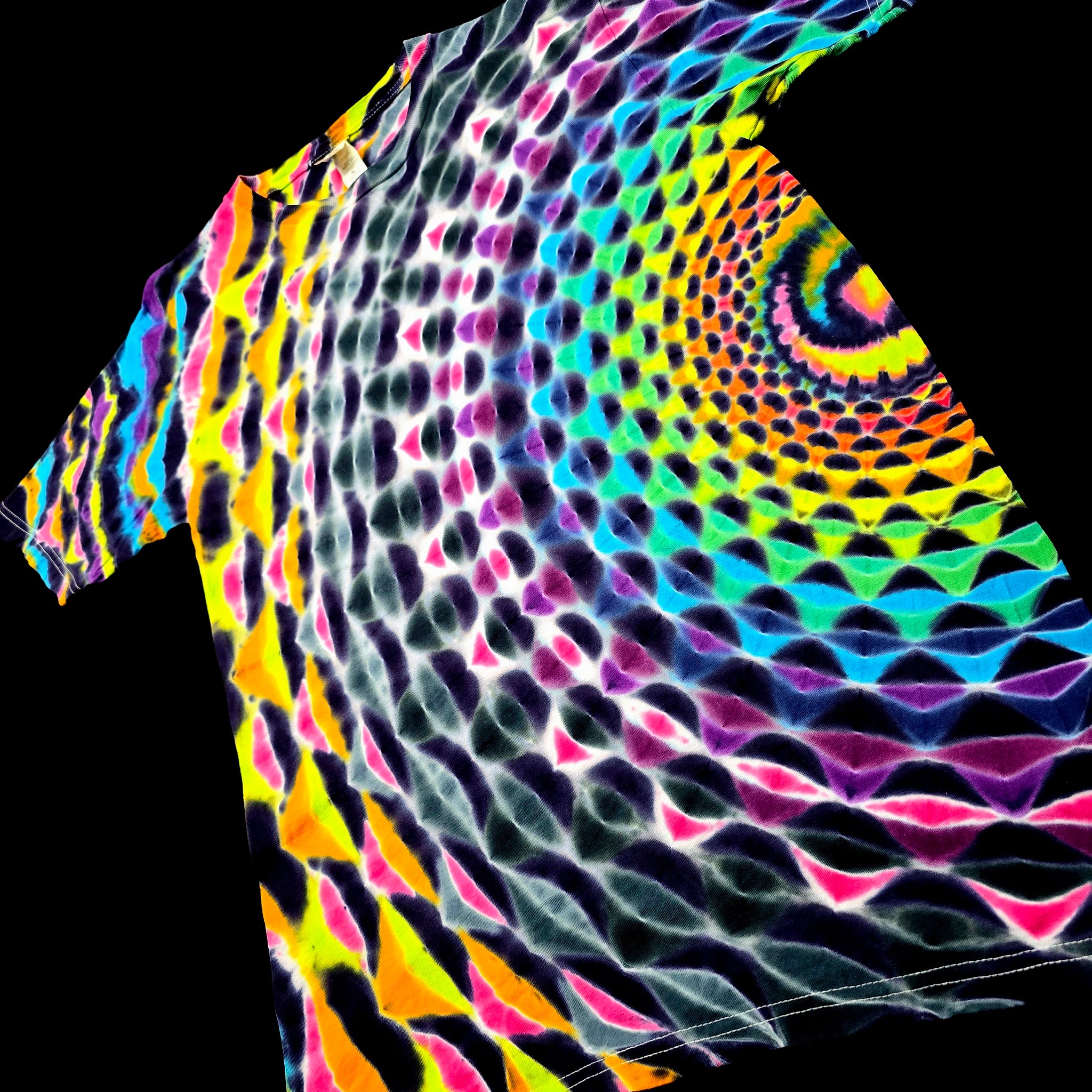 A short-sleeve t-shirt with a vibrant, psychedelic spiral pattern in neon yellow, pink, green, blue, and purple over a black base, shown against a solid black background.