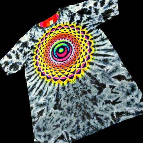 A short-sleeve tie-dye T-shirt laid flat on a black background, featuring a large multicolor spiral mandala graphic on the chest over a black, white, and gray tie-dye pattern.