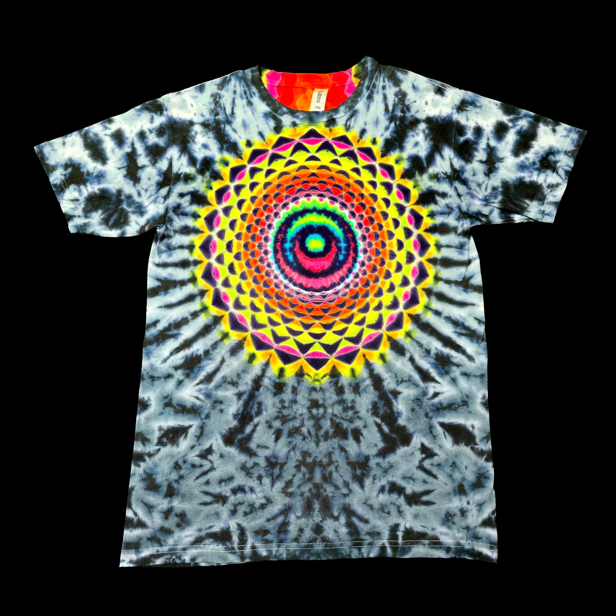 A short-sleeve tie-dye t-shirt featuring a large, vibrant mandala design in the center. The shirt has a blue, gray, and white tie-dye pattern with a bright multicolor spiral mandala graphic on the chest, displayed against a solid black background.