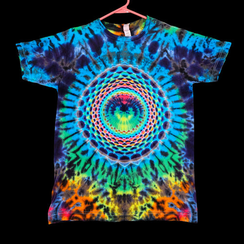A short-sleeve tie-dye t-shirt hanging on a pink hanger against a solid black background. The shirt features a vibrant, symmetrical psychedelic spiral mandala pattern in blue, green, yellow, orange, and purple.