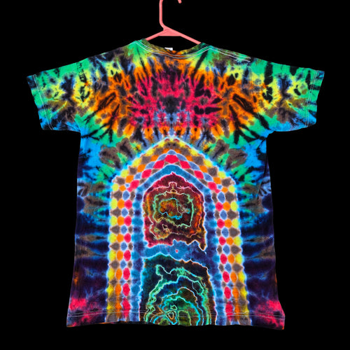 A short-sleeve tie-dye t-shirt hanging on a pink hanger against a solid black background. The shirt features a highly vibrant, symmetrical mandala-like tie-dye pattern with concentric arches and radial bursts of neon colors including green, blue, yellow, orange, pink, and purple.
