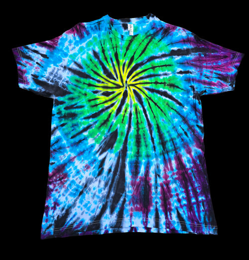 A short-sleeve tie-dye t-shirt featuring a vibrant spiral pattern with bright green, blue, purple, and black dye radiating from the center, shown against a solid black background.