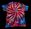 A short-sleeve crewneck tie-dye t-shirt featuring a vibrant spiral pattern with red, blue, black, and yellow-green tones, displayed against a solid black background.
