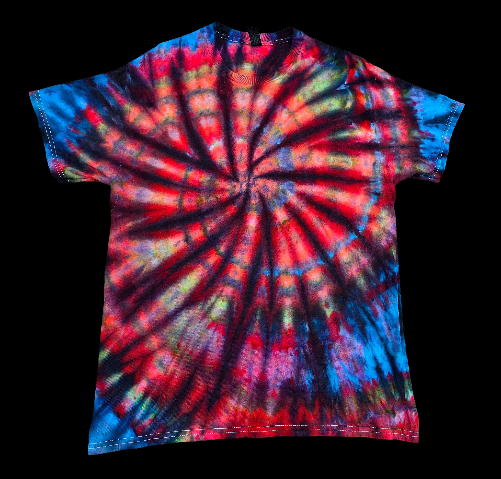 A short-sleeve crewneck tie-dye t-shirt featuring a vibrant spiral pattern with red, blue, black, and yellow-green tones, displayed against a solid black background.