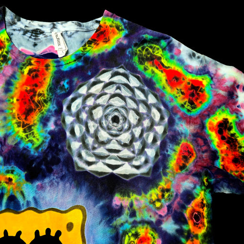 A close-up of a tie-dye t-shirt featuring a large white geometric flower design in the center, surrounded by vibrant neon rainbow tie-dye patterns, with a yellow graphic at the bottom.