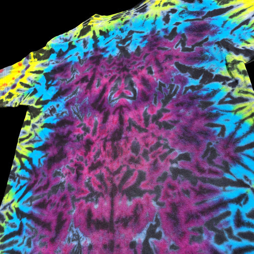 A close-up of a tie-dye t-shirt featuring a vibrant neon pattern of magenta pink, cyan blue, yellow, and black.