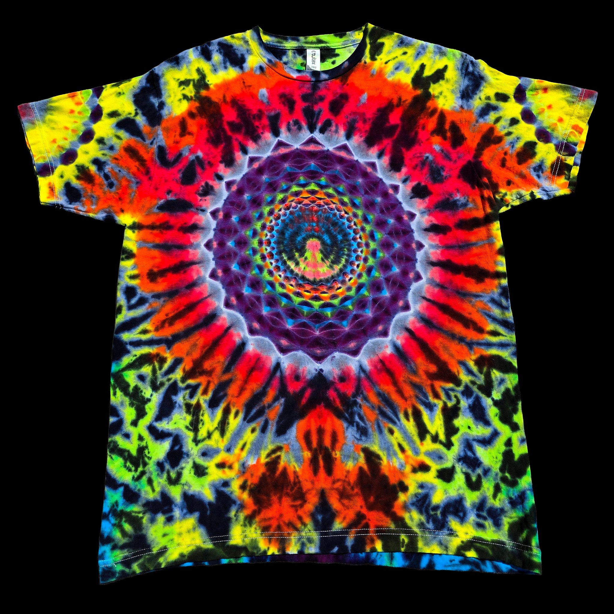 A short-sleeve crewneck t-shirt featuring a vibrant, symmetrical psychedelic tie-dye pattern with a central mandala and rainbow spiral, displayed flat against a solid black background.