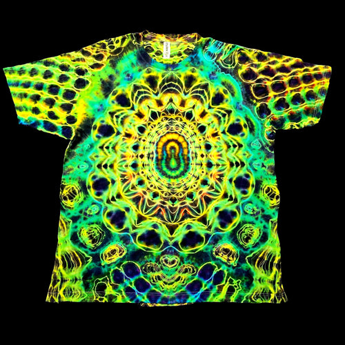 A short-sleeve crewneck t-shirt featuring a vibrant, symmetrical psychedelic mandala pattern in neon green, yellow, blue, and black, displayed flat against a solid black background.