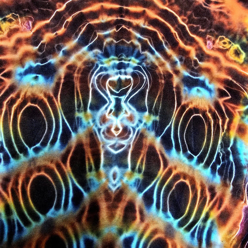A close-up of a tie-dye fabric with a highly symmetrical, psychedelic pattern featuring glowing neon orange, yellow, blue, and white concentric shapes on a dark base.