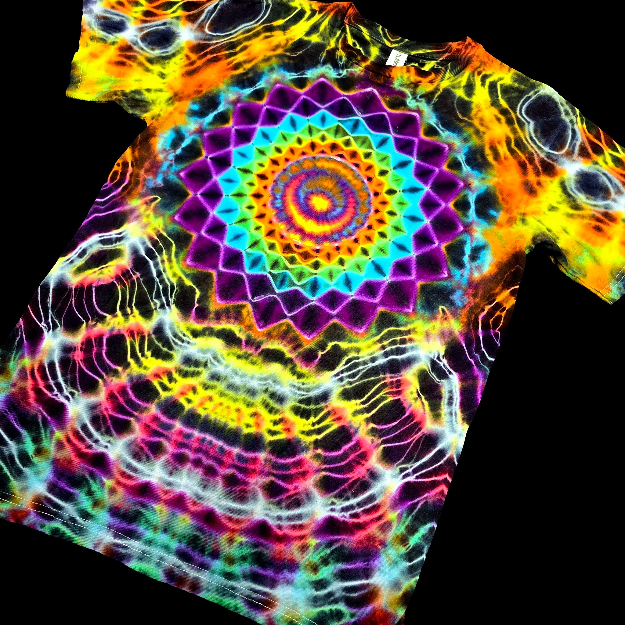 A short-sleeve tie-dye T-shirt with a large rainbow mandala design on the chest, displayed against a solid black background.