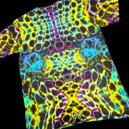 A short-sleeve crewneck t-shirt featuring a vibrant, neon psychedelic tie-dye pattern with glowing outlines of cells or bubbles in yellow, green, blue, pink, and purple over a black base.