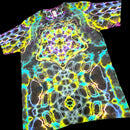 A short-sleeve crewneck t-shirt featuring a vibrant, symmetrical psychedelic kaleidoscope pattern with neon yellow, cyan, purple, and white glowing lines over a dark base.
