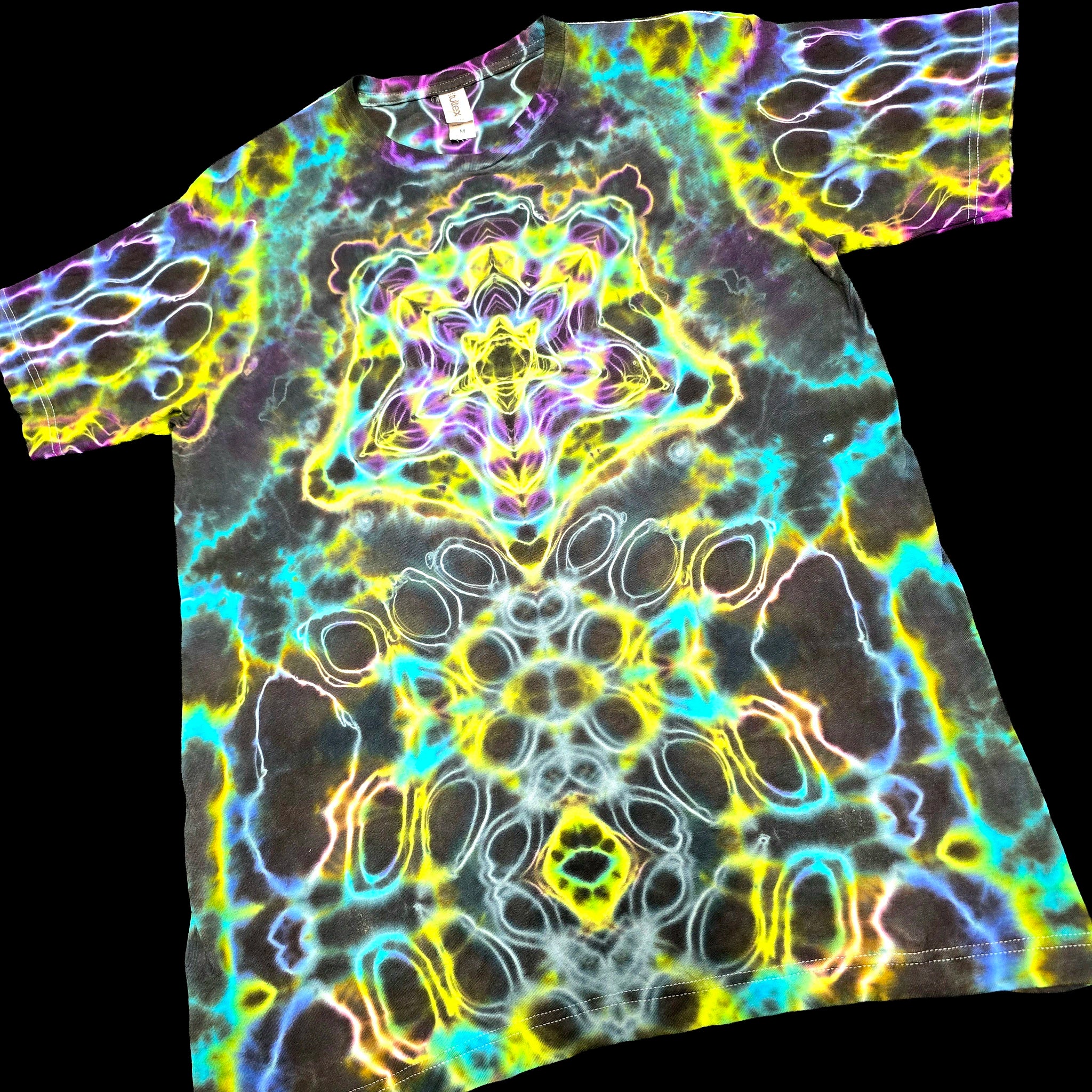 A short-sleeve crewneck t-shirt featuring a vibrant, symmetrical psychedelic kaleidoscope pattern with neon yellow, cyan, purple, and white glowing lines over a dark base.