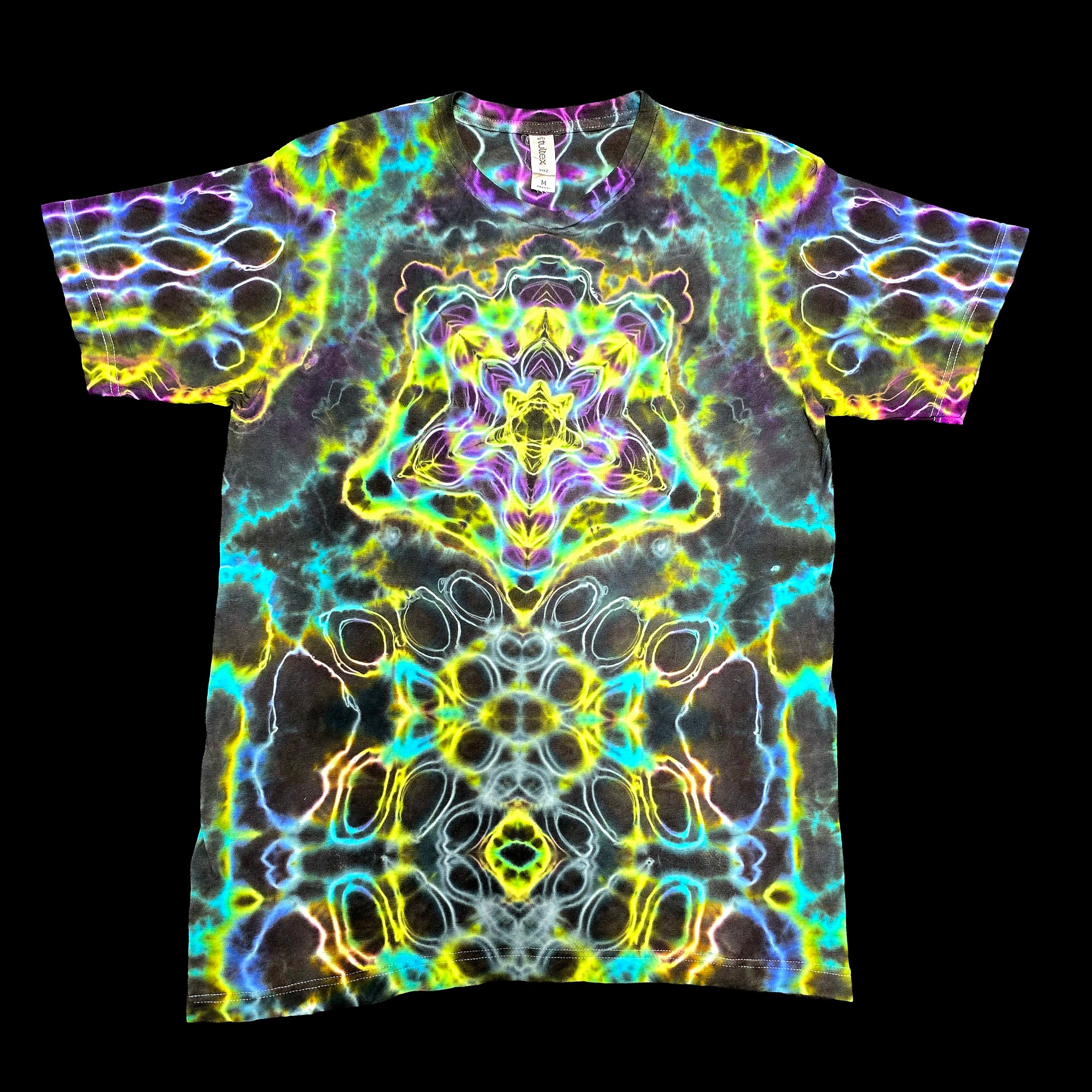 A short-sleeve crewneck t-shirt featuring a vibrant, symmetrical psychedelic kaleidoscope pattern with neon yellow, green, blue, purple, and pink glowing lines over a dark charcoal base.