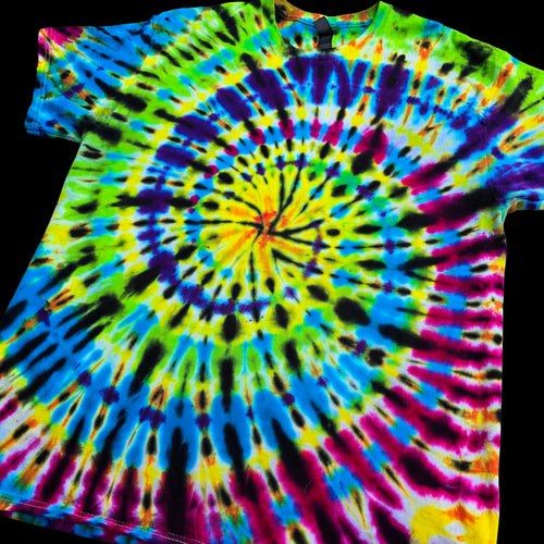 A short-sleeve tie-dye t-shirt featuring a vibrant spiral pattern with neon yellow, green, blue, purple, pink, and black dye bursts, shown against a solid black background.