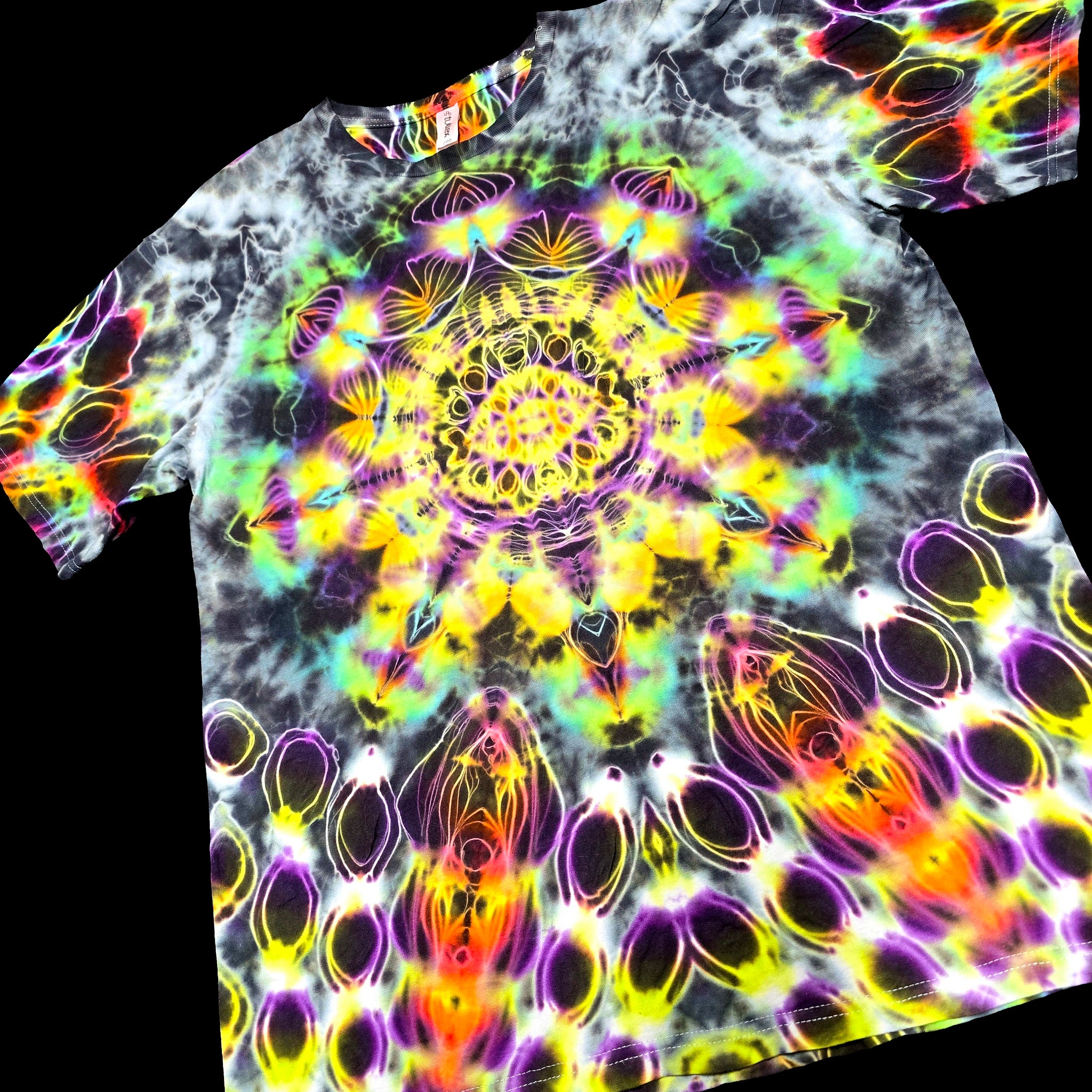 A short-sleeve crewneck t-shirt featuring a vibrant, multicolor psychedelic mandala print on a black base, shown against a solid black background.