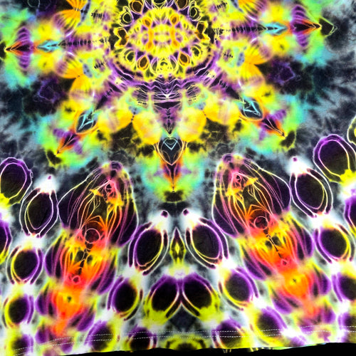 A close-up of a tie-dye fabric featuring a vibrant, symmetrical psychedelic pattern with neon yellow, purple, pink, orange, and green on a dark base.