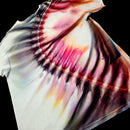 A close-up of a white tie-dye t-shirt with a circular pattern of pink, purple, and orange dye bleached around a black edge, set against a solid black background.