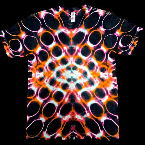 A short-sleeve tie-dye t-shirt with a symmetrical, kaleidoscopic pattern of black, orange, pink, and white circular motifs, displayed flat against a solid black background.