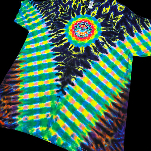 A short-sleeve tie-dye T-shirt laid flat on a black background, featuring a spiral sunburst pattern with neon green, yellow, blue, purple, and orange tones, plus a circular mandala-style graphic at the center chest.