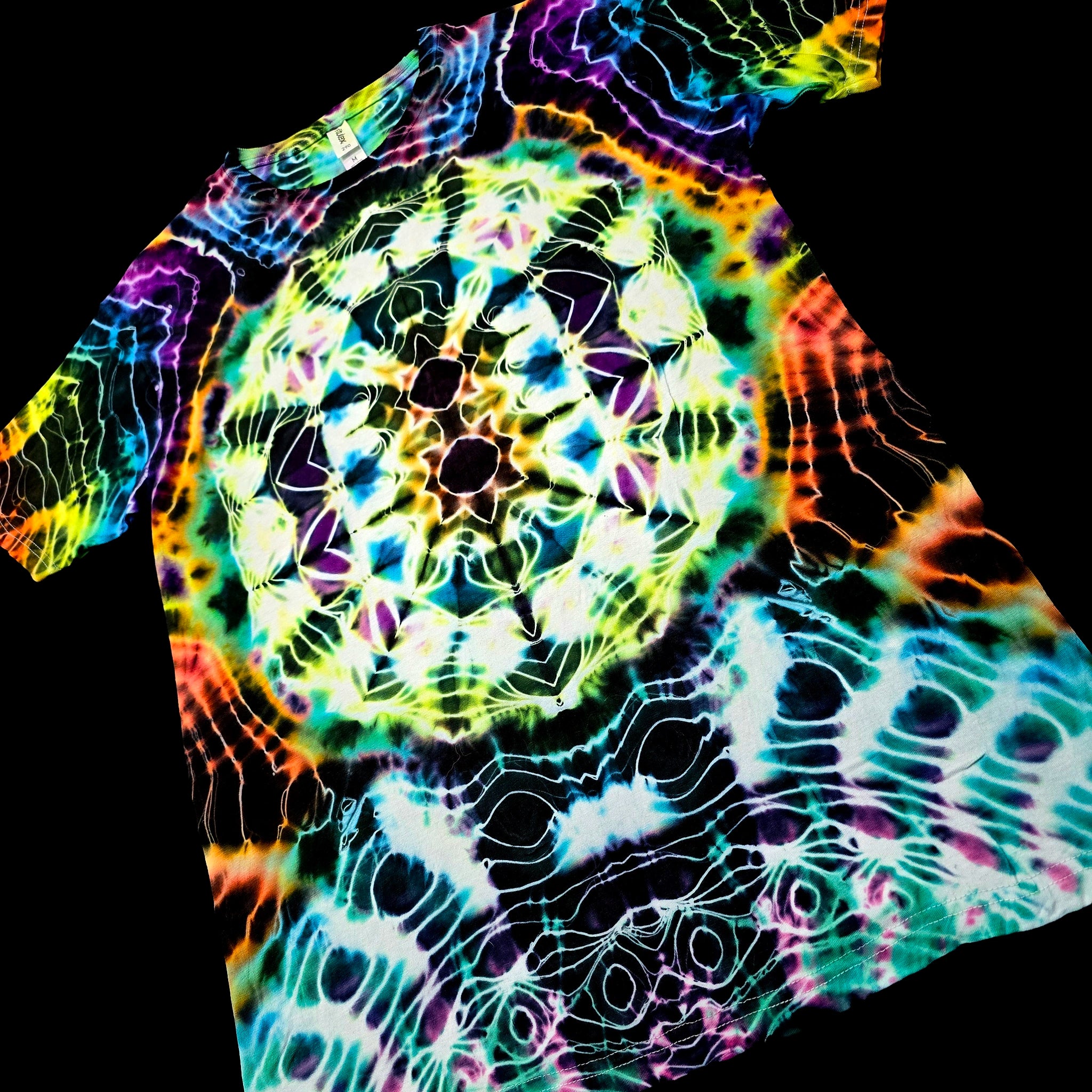 A short-sleeve t-shirt featuring a vibrant, psychedelic tie-dye pattern with a central mandala-like circular design and wavy rainbow lines over a black base.