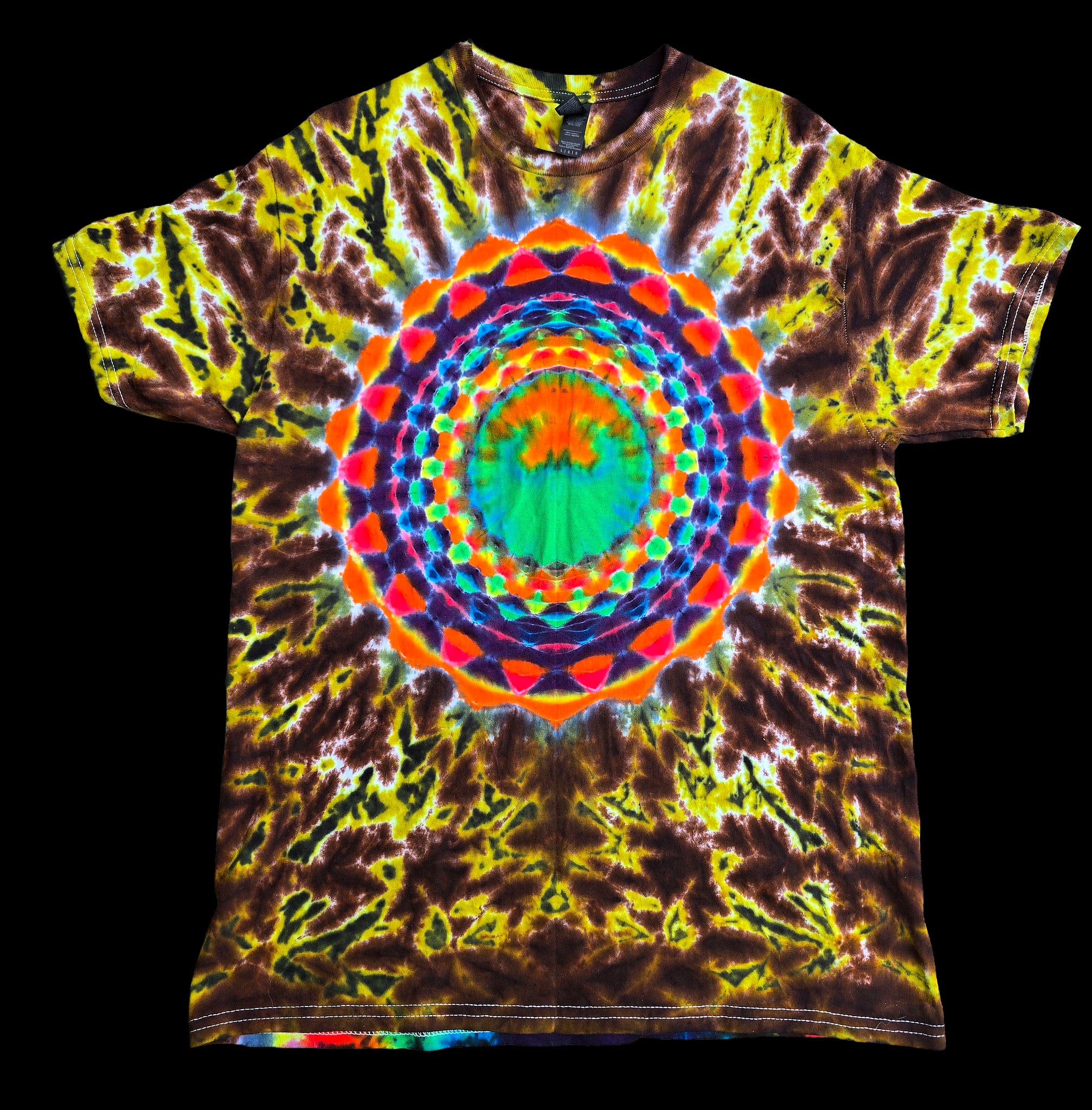 A short-sleeve crewneck t-shirt featuring a vibrant, multicolor tie-dye pattern with a large, symmetrical mandala design printed in the center. The base color is a mix of yellow, green, and dark brown, with the central mandala adding bright accents of orange, red, blue, and green.
