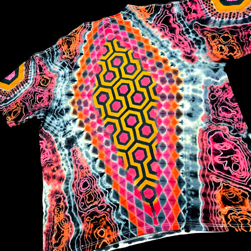 Back angled perspective of tie dye tee detailing yellow and black hexagonal carpet design and pink honeycomb diamond frame