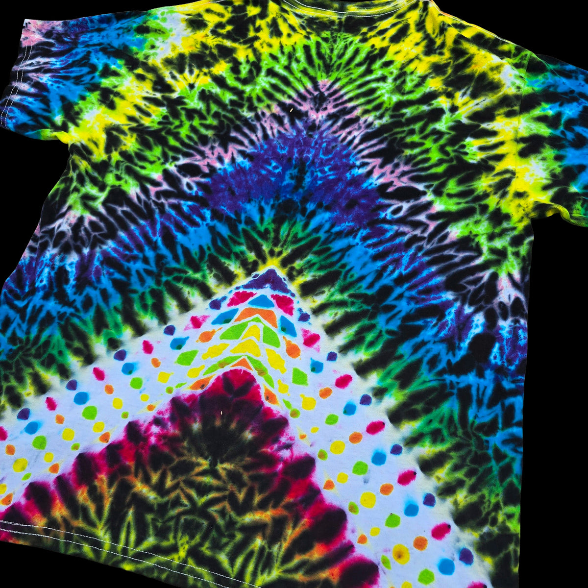 A short-sleeve tie-dye T-shirt laid flat on a black background, featuring a rainbow spiral pattern with a white lower section decorated with multicolored polka dots.