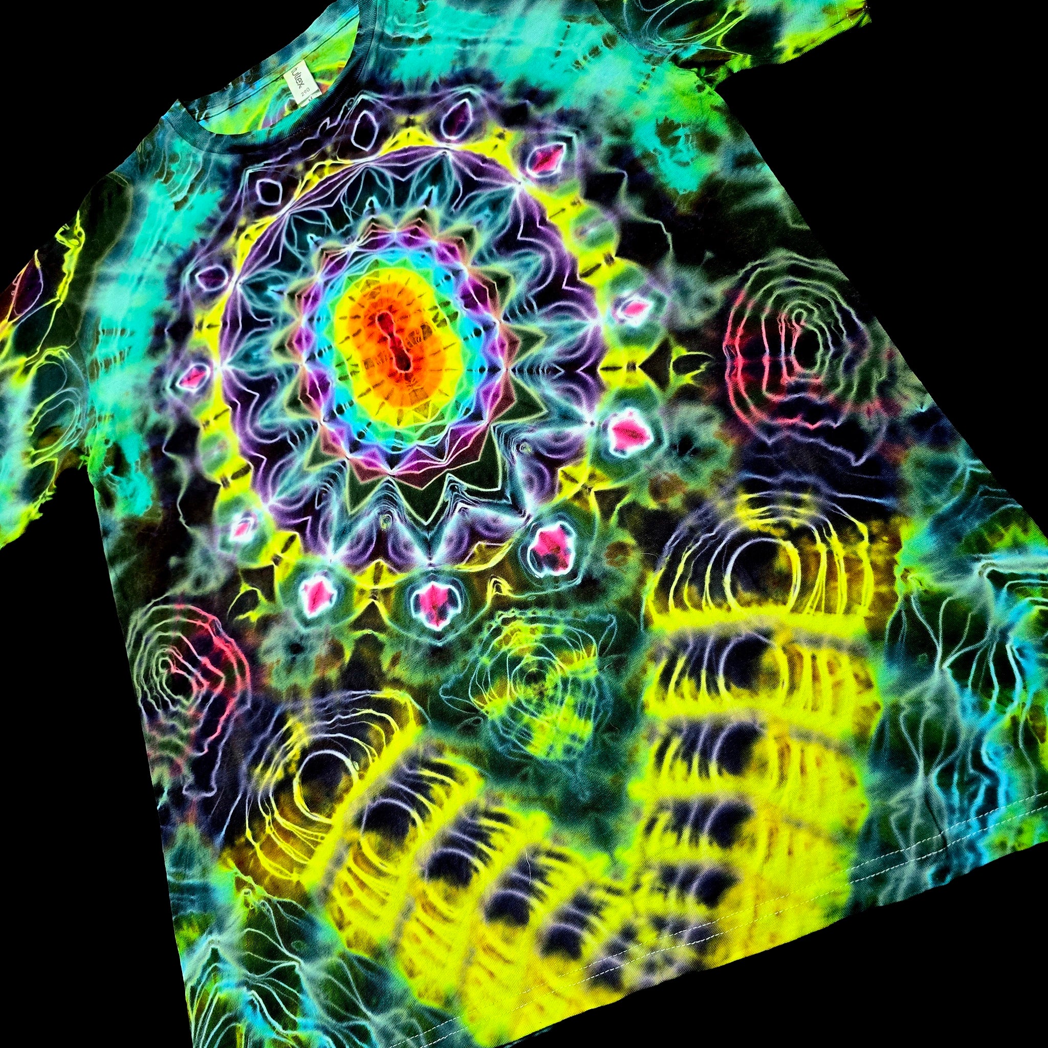 A short-sleeve t-shirt featuring a vibrant, psychedelic tie-dye mandala pattern with neon yellow, green, blue, pink, and purple colors, shown against a solid black background.